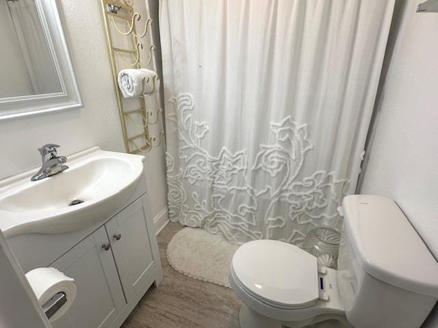 bathroom featuring vanity, hardwood / wood-style flooring, and toilet