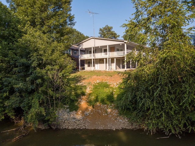 rear view of property featuring a balcony and a water view