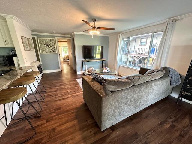 living room featuring crown molding, a textured ceiling, ceiling fan, and dark hardwood / wood-style flooring