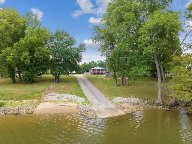 view of dock with a water view and a lawn