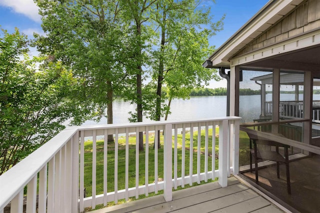 wooden terrace with a water view, a sunroom, and a lawn