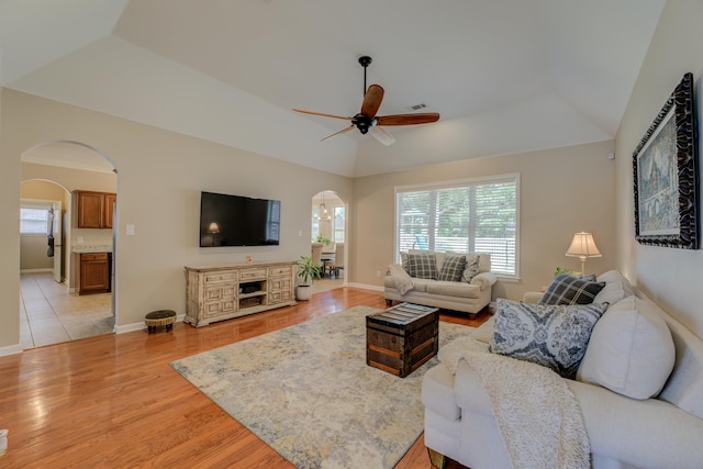 living room featuring vaulted ceiling, ceiling fan, a raised ceiling, and light hardwood / wood-style floors