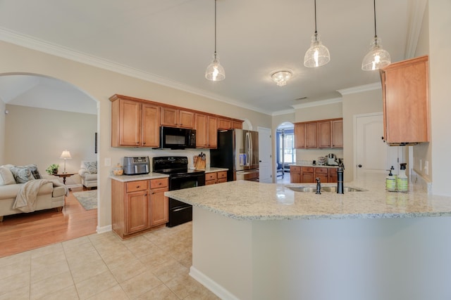 kitchen with pendant lighting, sink, light stone counters, and black appliances