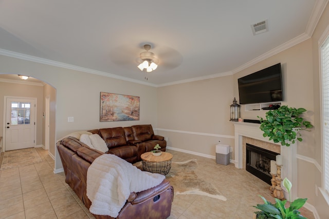 tiled living room with ceiling fan, ornamental molding, and a tile fireplace