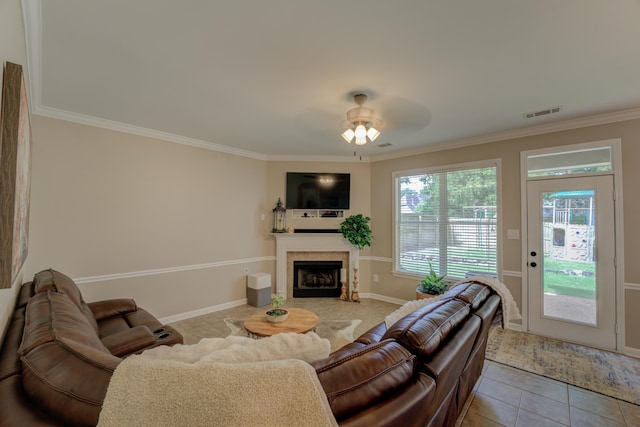 tiled living room with a fireplace, ornamental molding, and ceiling fan