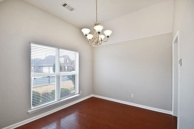 empty room featuring dark hardwood / wood-style floors, a wealth of natural light, and a chandelier