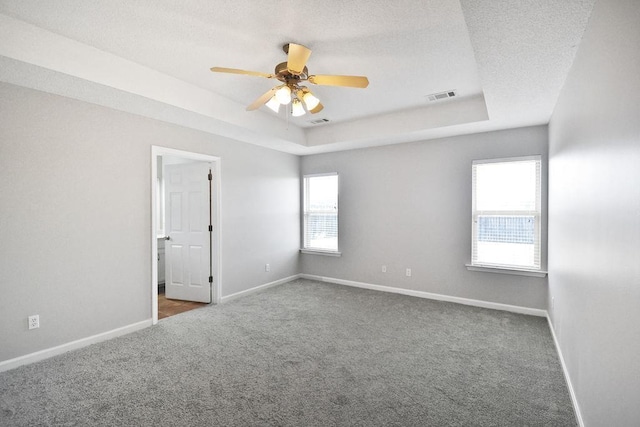 carpeted spare room featuring ceiling fan, a tray ceiling, and a textured ceiling