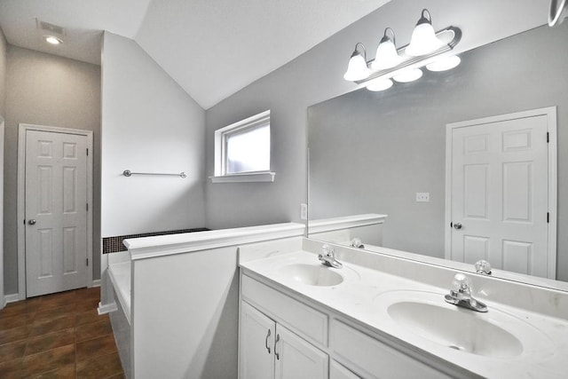 bathroom with vanity, vaulted ceiling, and a tub