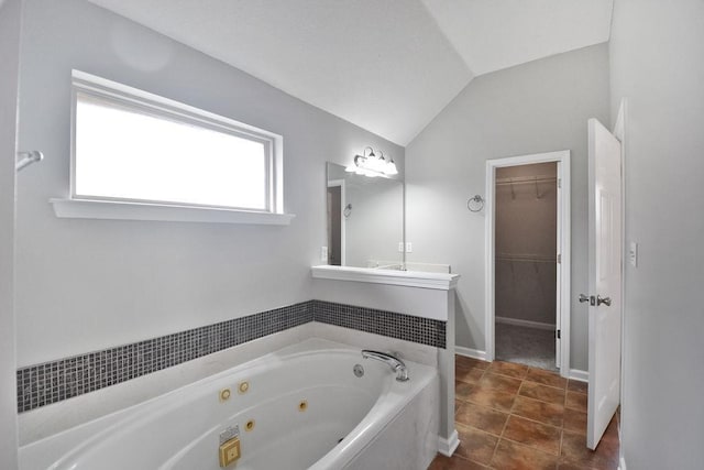 bathroom with vaulted ceiling, a washtub, tile patterned floors, and vanity