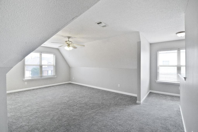 additional living space featuring lofted ceiling, a textured ceiling, ceiling fan, and carpet