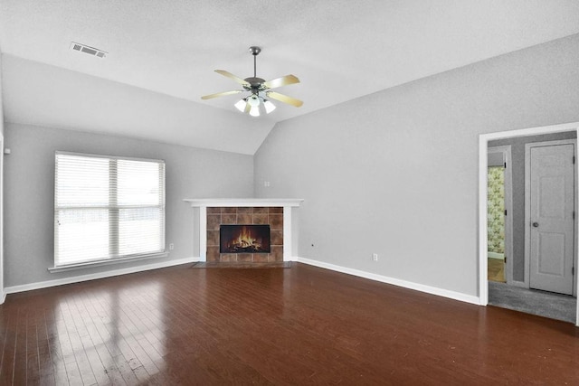 unfurnished living room with dark wood-type flooring, a tile fireplace, ceiling fan, and vaulted ceiling