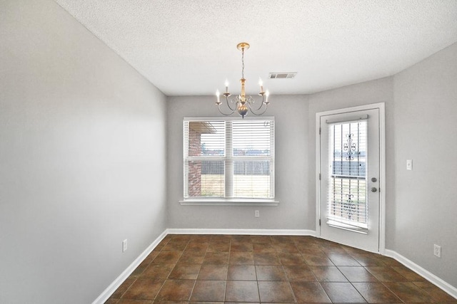 unfurnished dining area featuring an inviting chandelier, a textured ceiling, and a healthy amount of sunlight