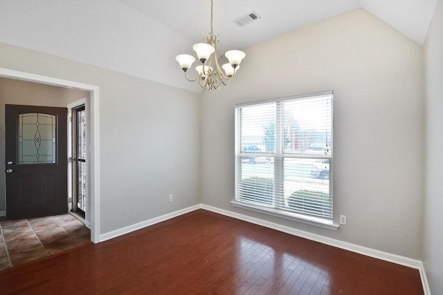 spare room featuring hardwood / wood-style flooring, lofted ceiling, and a chandelier