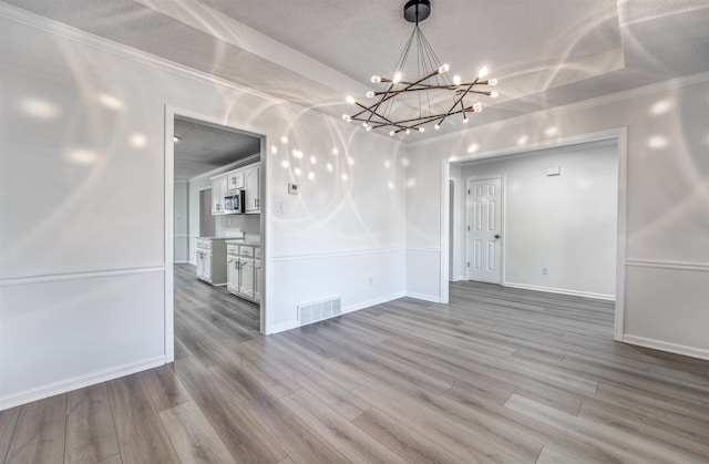 unfurnished dining area with ornamental molding, a textured ceiling, and light hardwood / wood-style floors