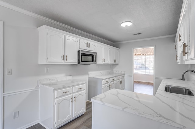 kitchen featuring sink, ornamental molding, kitchen peninsula, and white cabinets