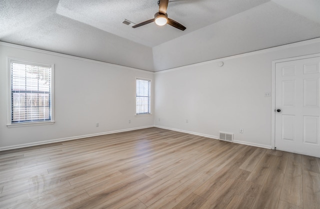 empty room featuring ceiling fan, vaulted ceiling, a textured ceiling, and light wood-type flooring