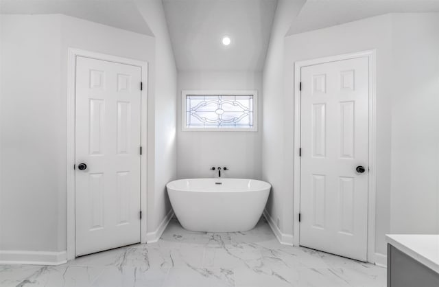 bathroom featuring vanity, a bath, and vaulted ceiling