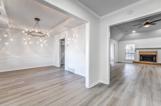 unfurnished dining area with ornamental molding, a brick fireplace, ceiling fan with notable chandelier, and light hardwood / wood-style flooring