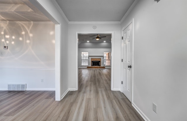 corridor with ornamental molding and light hardwood / wood-style floors