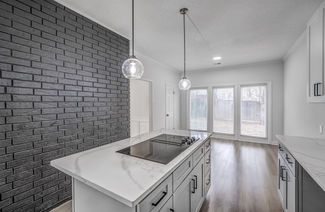 kitchen with white cabinetry, black electric stovetop, wood-type flooring, light stone countertops, and decorative light fixtures