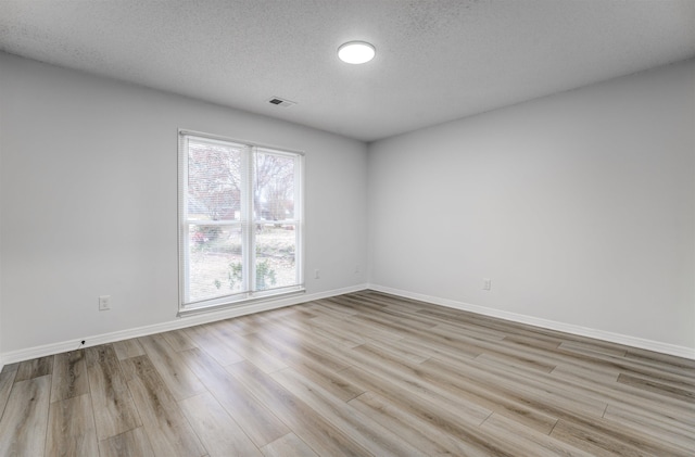 spare room with a textured ceiling and light wood-type flooring