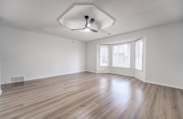 spare room featuring ceiling fan, light hardwood / wood-style floors, and a textured ceiling