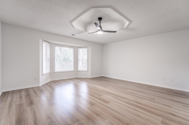 spare room with a textured ceiling, ceiling fan, and light hardwood / wood-style flooring