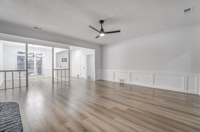 empty room featuring ceiling fan with notable chandelier, a textured ceiling, and light wood-type flooring