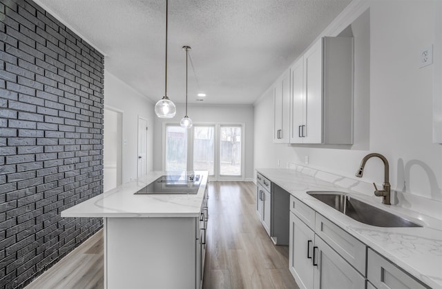 kitchen featuring sink, a center island, light wood-type flooring, pendant lighting, and white cabinets