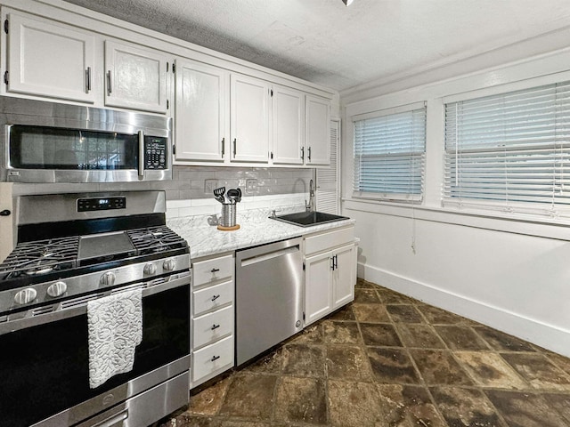 kitchen with sink, backsplash, stainless steel appliances, a textured ceiling, and white cabinets