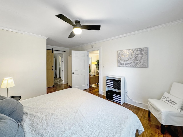 bedroom featuring ornamental molding, a barn door, dark hardwood / wood-style floors, and ceiling fan