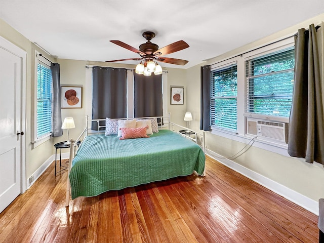 bedroom featuring hardwood / wood-style flooring, cooling unit, and ceiling fan