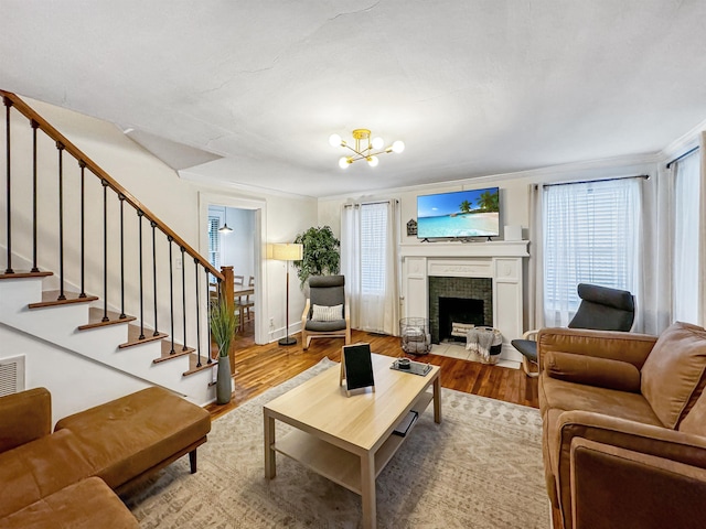 living room with an inviting chandelier, a healthy amount of sunlight, a fireplace, and hardwood / wood-style floors