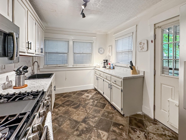 kitchen featuring sink, appliances with stainless steel finishes, ornamental molding, a textured ceiling, and white cabinets