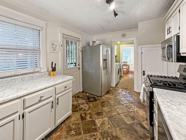 kitchen featuring washing machine and dryer, appliances with stainless steel finishes, white cabinets, and a textured ceiling