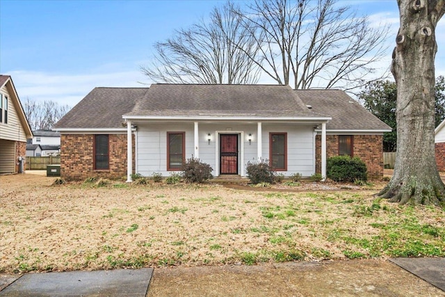 single story home with cooling unit, fence, brick siding, and a shingled roof