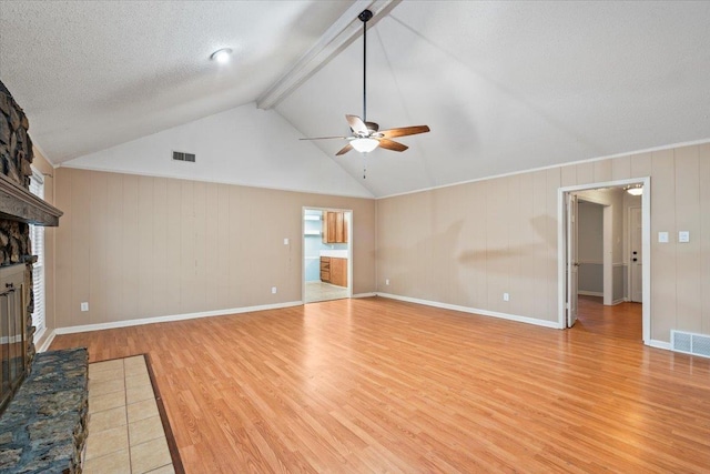 unfurnished living room with lofted ceiling with beams, light hardwood / wood-style flooring, a textured ceiling, a large fireplace, and ceiling fan