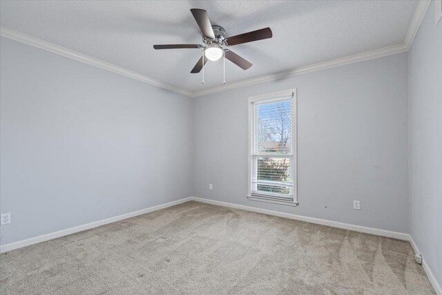 carpeted empty room featuring ceiling fan, a textured ceiling, baseboards, and ornamental molding