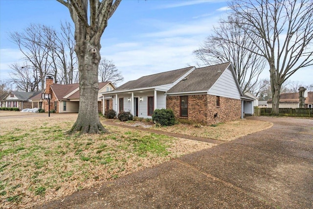 view of front facade with aphalt driveway, brick siding, a garage, and fence