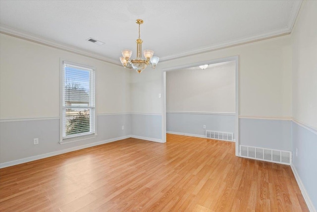 spare room with an inviting chandelier, ornamental molding, and light hardwood / wood-style floors