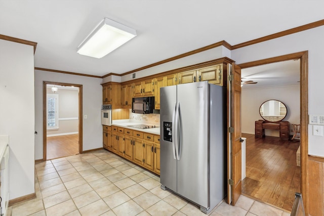 kitchen featuring tasteful backsplash, light tile patterned floors, crown molding, and black appliances