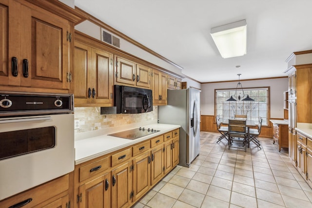 kitchen featuring crown molding, tasteful backsplash, light tile patterned floors, pendant lighting, and black appliances