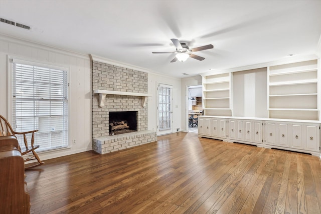 unfurnished living room featuring crown molding, a brick fireplace, hardwood / wood-style floors, and built in features