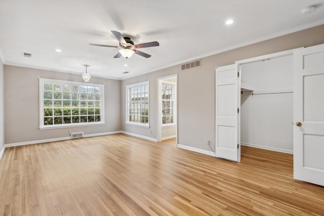 unfurnished bedroom with a spacious closet, ornamental molding, a closet, ceiling fan, and light hardwood / wood-style floors