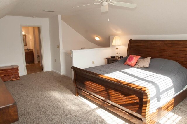 carpeted bedroom featuring ceiling fan, ensuite bathroom, and vaulted ceiling