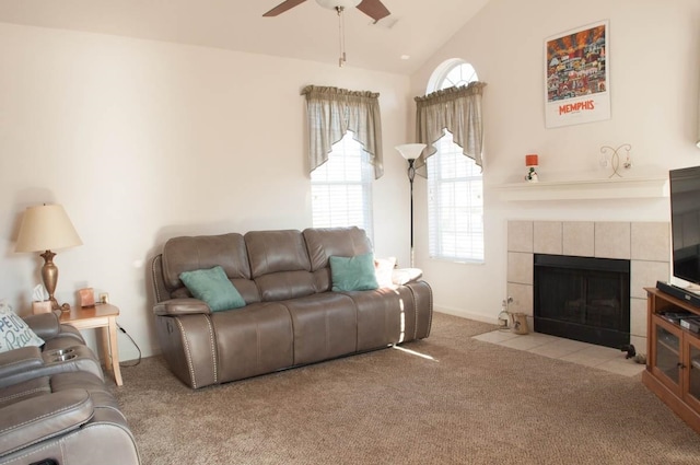 carpeted living room featuring a tiled fireplace, vaulted ceiling, and ceiling fan