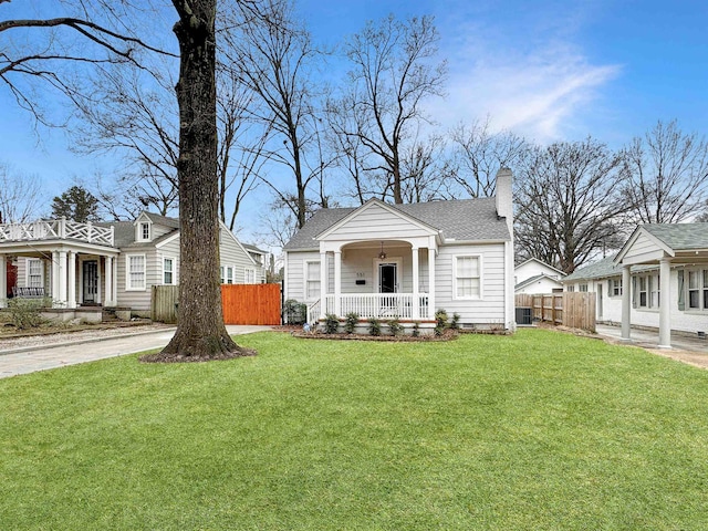 view of front of home with cooling unit, a front yard, and covered porch