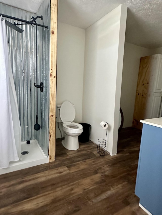 bathroom featuring hardwood / wood-style floors, a textured ceiling, curtained shower, and toilet