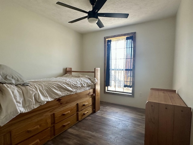 bedroom featuring dark hardwood / wood-style flooring, ceiling fan, and a textured ceiling