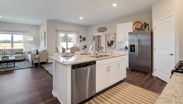 kitchen featuring sink, dark wood-type flooring, white cabinetry, stainless steel appliances, and a center island with sink